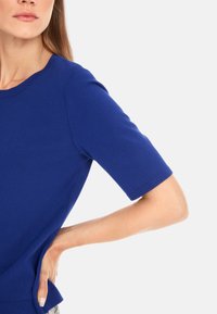Blue short-sleeve top made of smooth fabric with a round neckline. The design features clean lines and a relaxed fit.