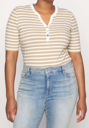 Tannede og hvide stribede ribbet top med korte ærmer og V-hals, med knapstolpe og tekstureret stof. Båret med lyseblå jeans.