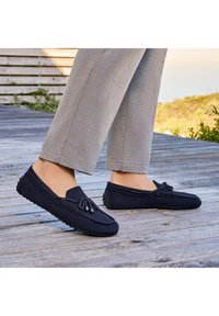 Marineblaue Slip-On-Schuhe aus Stoff mit strukturierten Oberflächen, ausgestattet mit einer Schnürung auf der Vorderseite und einer Gummisohle für besseren Halt.