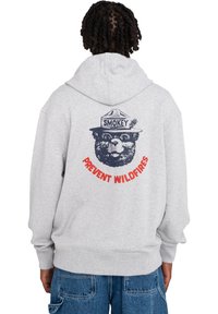 Gray hooded sweatshirt with a bear graphic wearing a ranger hat. Text reads "PREVENT WILDFIRES" in red curved letters beneath the graphic.