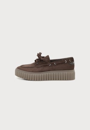 Brun ruskind platform loafer med tyk rillede gummisål og sløjfedetalje på snørebånd, vist på ensartet lyst baggrund.