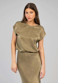 Haut olive, à manches courtes, avec une texture lisse et brillante et un col arrondi, associé à une jupe moulante assortie.