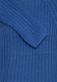 Pull en tricot bleu avec un design en rib à texture et des manches amples. Le tissu semble doux et légèrement volumineux.