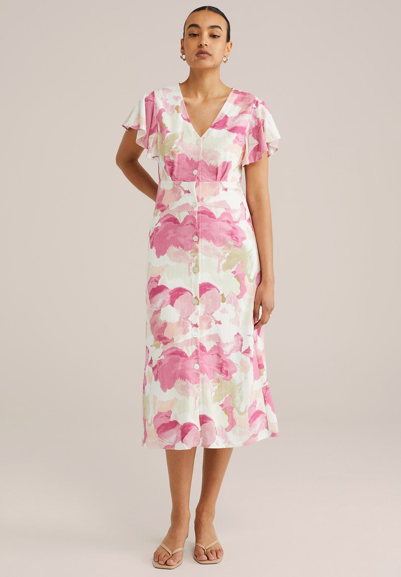 Robe midi florale avec des motifs roses et verts, manches courtes volantées, décolleté en V et boutons sur le devant. Fabriquée en tissu léger avec une coupe décontractée.