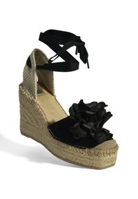 Schwarze Keil-ESPADRILLES mit einer strukturierten Jutesohle, Veloursleder-Obermaterial und einem Stoffblütenakzent. Schwarze Knöchelriemen wickeln sich um den Knöchel und werden darüber gebunden.