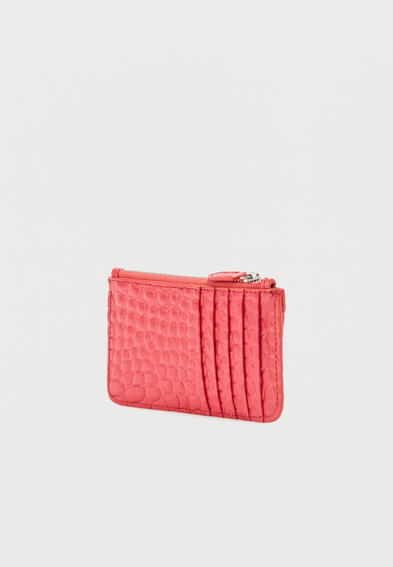 Small coral pink wallet with crocodile texture, zipper top, and five card slots on front.