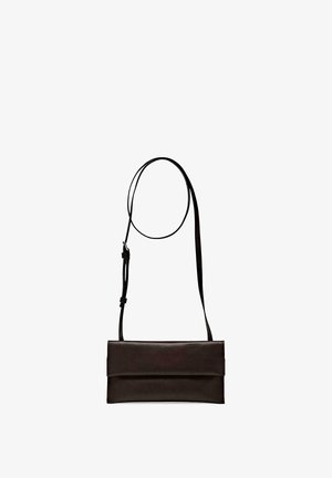 Zwarte leren crossbodytas met verstelbare dunne band en overslagklem, getoond tegen een witte achtergrond.