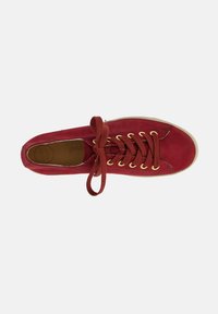 Sneaker in suede rosso con occhielli dorati, lacci rotondi e suola in gomma beige. L'interno presenta una soletta testurizzata con la dicitura "super soft."