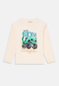 Hosszú ujjú krémszínű póló, színes grafikai mintával, amelyen egy zöld részletekkel díszített monster truck látható, valamint játékos "WOW!" felirattal. Puha pamut anyag.