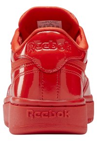 Błyszczący czerwony sneaker Reebok widziany z tyłu, z widocznymi wytłoczonymi logo Reebok na kołnierzu pięty i podeszwie.