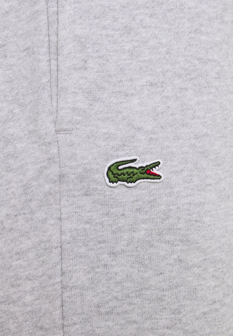 Męska szara bluza z miękkiej tkaniny, z małym, haftowanym zielonym logo krokodyla na lewej stronie klatki piersiowej.