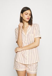 Korte mouwen, knoopsluiting pyjama set in zachte, lichte stof. Lichtroze met verticale strepen in paars en geel. Inclusief een borstzak.