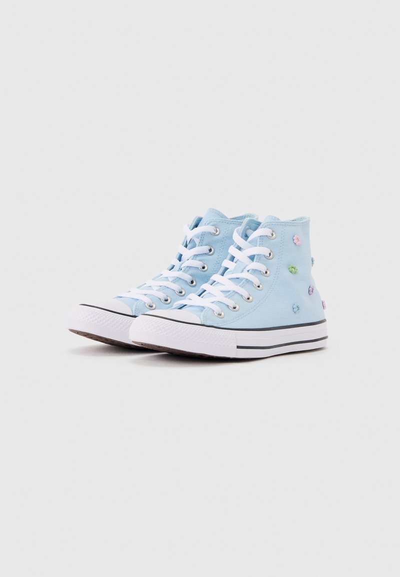 Sneakers alte azzurro chiaro con lacci bianchi, suole di gomma e piccoli ricami di fiori pastello sui lati su uno sfondo semplice.