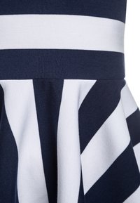 Námořnické a bílé pruhované šaty se dobře padnoucím živůtkem a rozšířenou sukňovitou částí. Tkanina má jemnou texturu s hladkými švy a čistými liniemi.