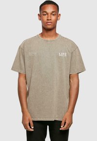Grå oversized t-shirt med korte ærmer, rund hals og hvid "LIFE" tekst på fronten. Lavet af blødt, struktureret bomuldsstof.