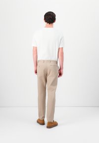 Hvid kortærmet skjorte parret med beige bukser, der har lige snit og to baglommer. Brune sko fuldender outfittet.