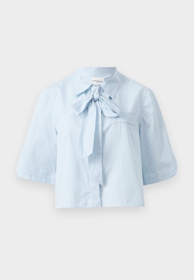 Lichtblauwe blouse met korte mouwen, gemaakt van textuurstof. Kenmerkt zich door een kraag met een voorste strikdetail en een enkele borstzak.