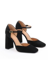 Black suede high-heeled shoes with a square toe, ankle strap, and a chunky heel. Smooth inner lining and minimalistic design details.