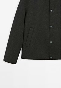 Dark gray wool jacket featuring a buttoned front, rounded collar, and side pockets with a smooth texture.