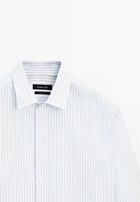 Camicia button-up a righe blu chiaro e bianche con colletto classico e tessuto leggermente texturizzato. Presenta un'etichetta del marchio nera all'interno del colletto.