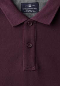Polo bordeaux en tissu texturé, col polo, patte de boutonnage à trois boutons et ourlet cousu. L'étiquette indique "STREET ONE MEN."