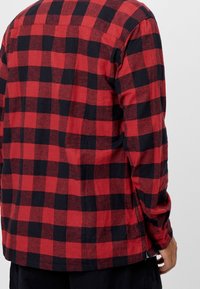 Rood-zwart geruit flanellen overhemd met lange mouwen, een rechte snit en zijslits. De stof lijkt zacht te zijn met een gestructureerde afwerking.