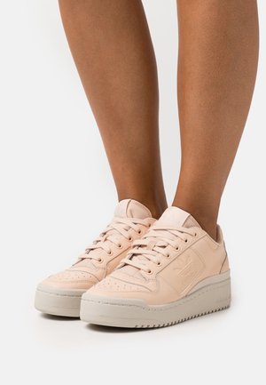 Baskets en cuir rose clair avec un bout perforé, lacets plats et détail de logo sur le côté ; semelle en caoutchouc avec un motif texturé.
