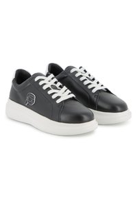 Μαύρα δερμάτινα αθλητικά παπούτσια με λευκά κορδόνια, στρογγυλή μύτη και παχιά λευκή λαστιχένια σόλα. Διαθέτουν λογότυπο στο πλάι και λεία υφή.