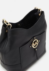 Czarna skórzana torba typu bucket z złotymi akcentami, z wyraźnym logo i teksturowanym wykończeniem. Otwarty górny z przestronnym wnętrzem.