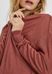 Oversized rustfarvet sweater lavet af blødt stof, med en afslappet pasform, ribstrikkede manchetter og et draperet design omkring skuldrene.
