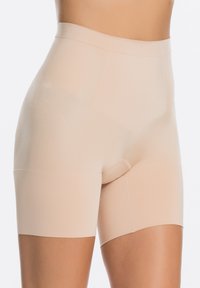 Beige shapewear shorts met een hoge tailleband, een gladde textuur en een naadloos ontwerp, met lichte bedekking voor comfort en ondersteuning.