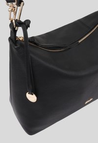 Sac à épaule en cuir noir avec une texture lisse, une fermeture éclair dorée et une petite étiquette avec un emblème. Dispose d'une seule bandoulière pour le port.