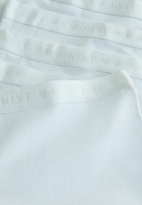Weiße Baumwollslips mit eingeprägtem "NEXT"-Logo und Herzmuster entlang des Bundes, ausgestattet mit glattem Stoff und nahtlosem Design.