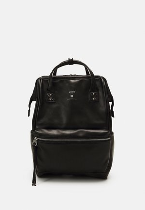 Zaino in pelle nera con manici superiori, tasca frontale con cerniera e logo "anello" su sfondo bianco semplice.