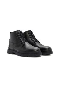 Botas negras de cuero hasta el tobillo con acabado texturizado, punteras redondas, cierre de cordones en la parte delantera y suelas de goma gruesa. Tienen un talón reforzado y detalles en los laterales.