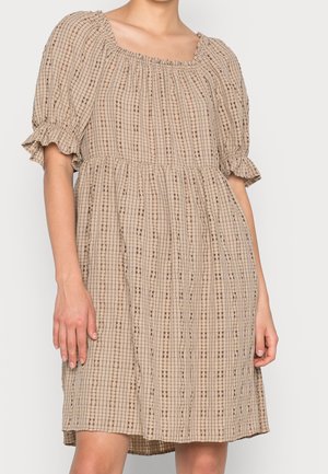 Beżowa sukienka w kratę z bufkami i marszczonym dekoltem, noszona przez osobę z widocznymi ramionami i nogami na jednolitym tle.