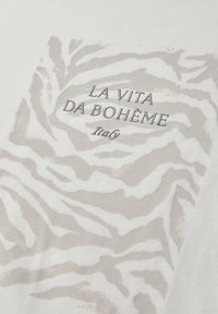 Beige en wit zebrapatroon met de tekst "LA VITA DA BOHÈME Italy" in zwart gedrukt op stof.
