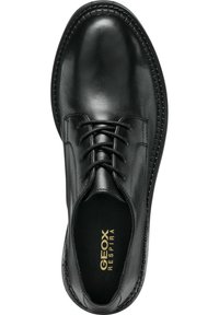 Chaussure noire en cuir avec un bout arrondi, design à lacets et marquage en relief à l'intérieur. Une couture texturée le long du bord ajoute du détail.