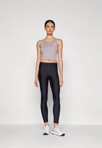 Svetlo siva atletska kratka majica in črne visokodežne pajkice z gladko teksturo in prilegajočim se dizajnom, dopolnjeni z belimi tekaškimi copati.