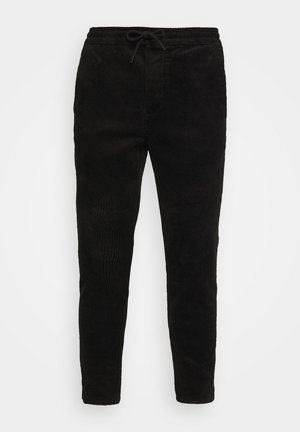 Schwarze Cordhosen mit elastischem Bund und Kordelzug, tapered Legs und vertikaler Rippstruktur.