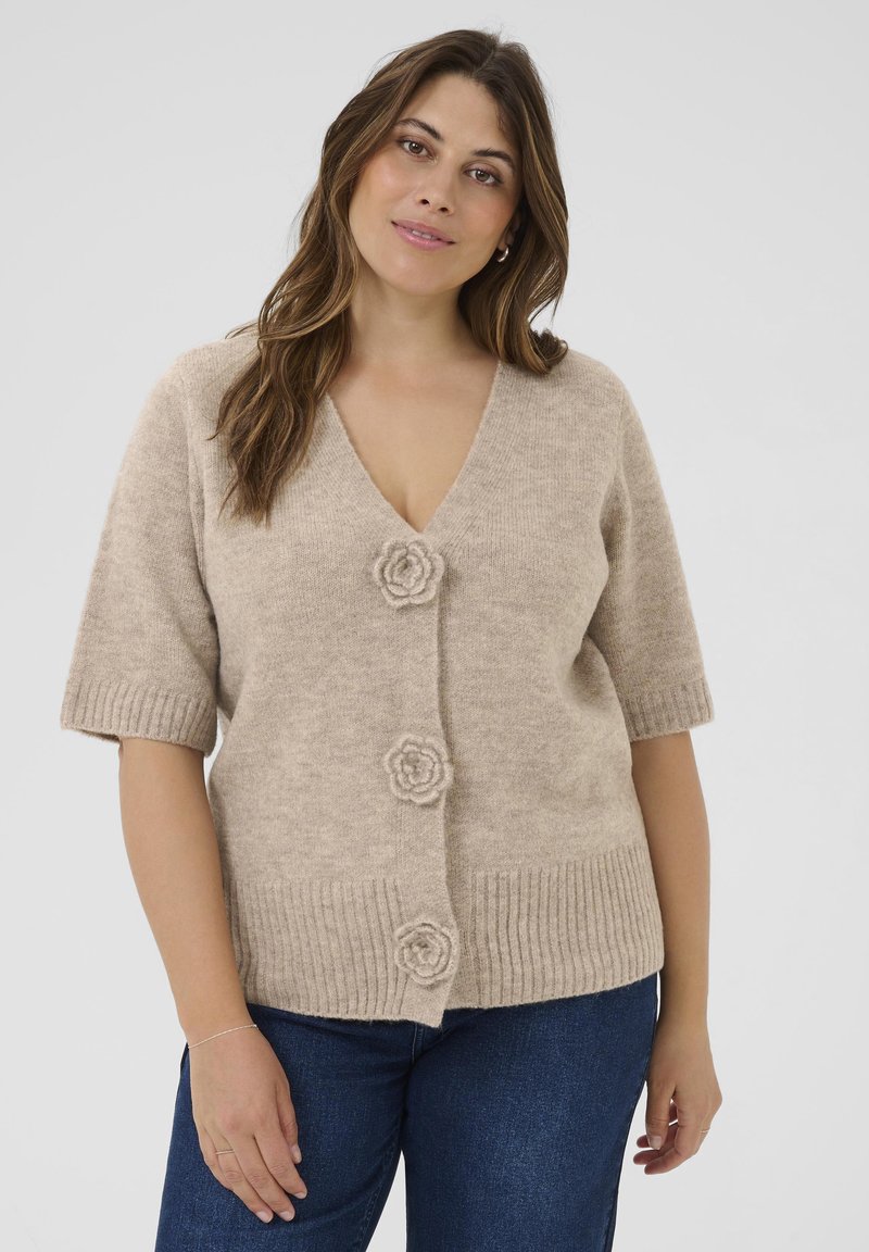 Cardigan beige en maille avec manches courtes, col en V, ourlet côtelé et trois boutons en forme de fleur à l'avant. Texture douce et coupe décontractée.