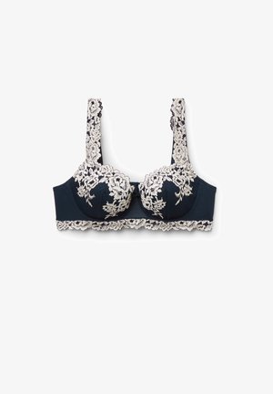 Tmavě modrá podprsenka s kosticemi s bílým květinovým krajkovým potahem na košíčcích, ramínkách a spodním okraji, zobrazena na bílém pozadí.