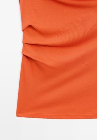 Oranges T-Shirt aus glattem Baumwollstoff, mit einem leicht gerafften Design an einer Seite und einem geraden Saum.