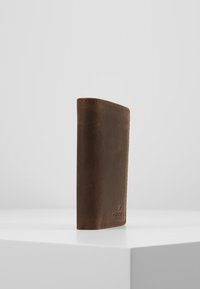 Hnědá kožená peněženka s hladkým povrchem, obdélníkovým tvarem a prošívanými okraji, vystavená vzpřímeně na jednobarevném pozadí.