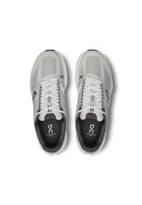Baskets de sport gris clair avec une tige en mesh, lacets blancs et intérieur gris foncé. Présente un logo et un design de semelle rembourrée.