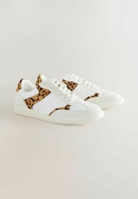 White sneakers with leopard print accents, featuring a textured upper, padded collar, and flat rubber sole. Laces and stitched details visible.