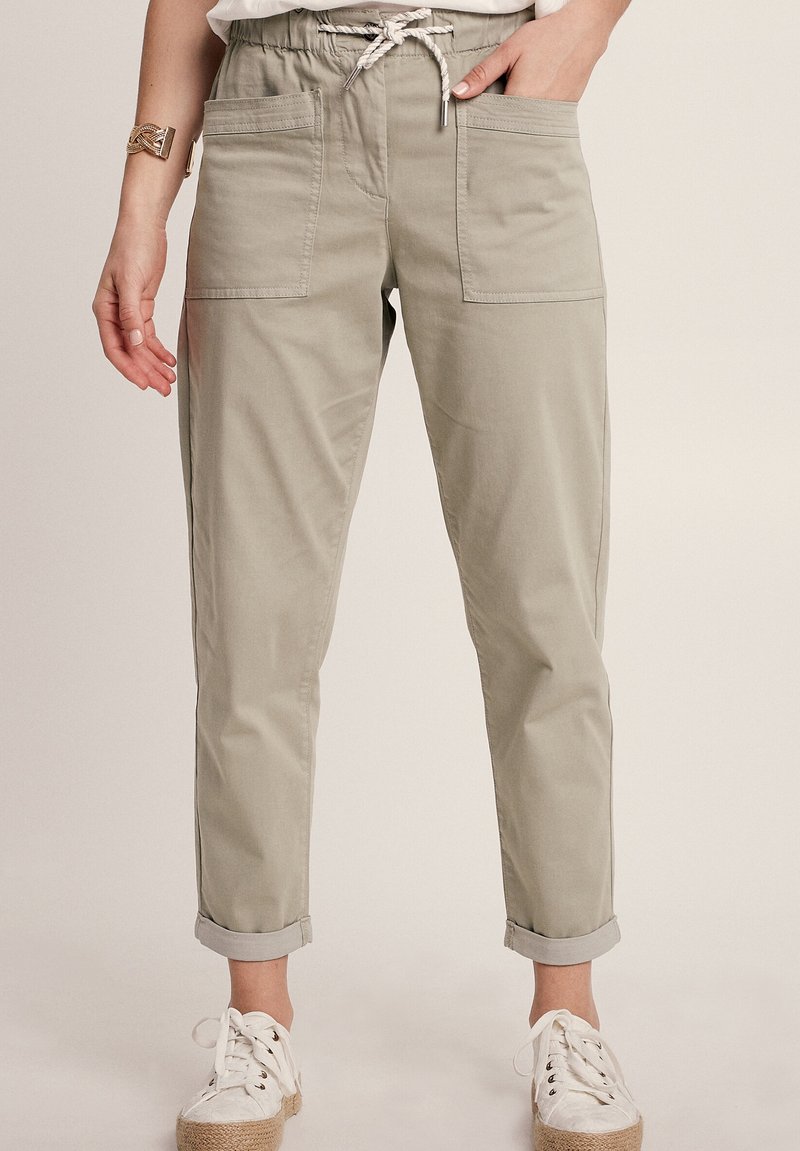 Helle graue, leichte, lässige Hose mit einem elastischen Bund, Kordelzug und umgeschlagenen Säumen; verfügt über Fronttaschen und eine glatte Textur.