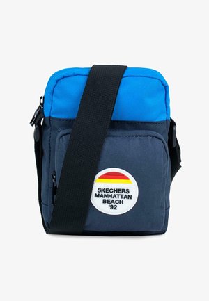 Pequeña bolsa cruzada con parte superior azul y cuerpo azul marino, cierre de cremallera, correa ajustable y un parche de logo redondo con texto y rayas.