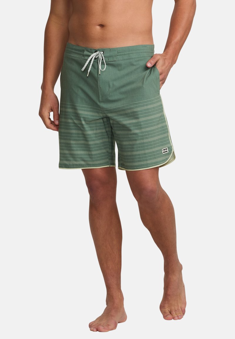 Zelené plavky s horizontálnymi pruhmi, s nastaviteľným pásom, bočnými vreckami a bielym akcentom pozdĺž lemu. Ľahký materiál.