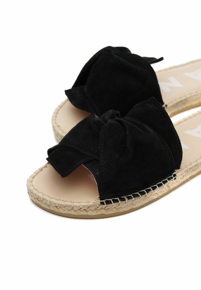 Sandali neri in suede con un dettaglio a fiocco annodato nella parte anteriore, caratterizzati da una suola in juta intrecciata in stile espadrilles e una soletta liscia di colore chiaro.